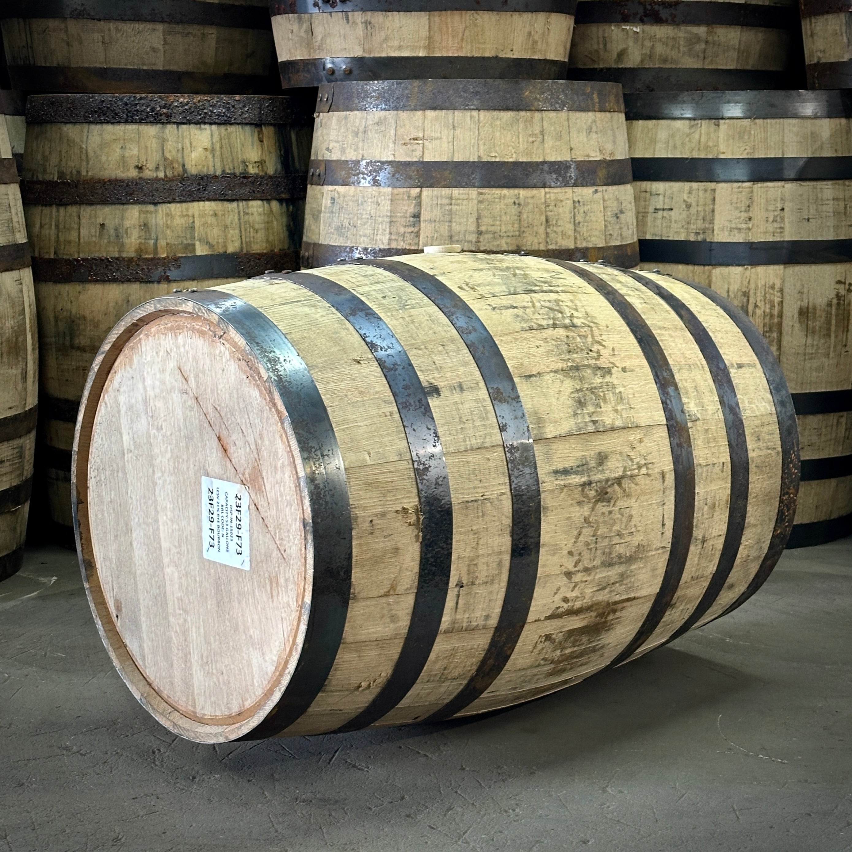 Wooden barrels with black bands stacked in a warehouse setting