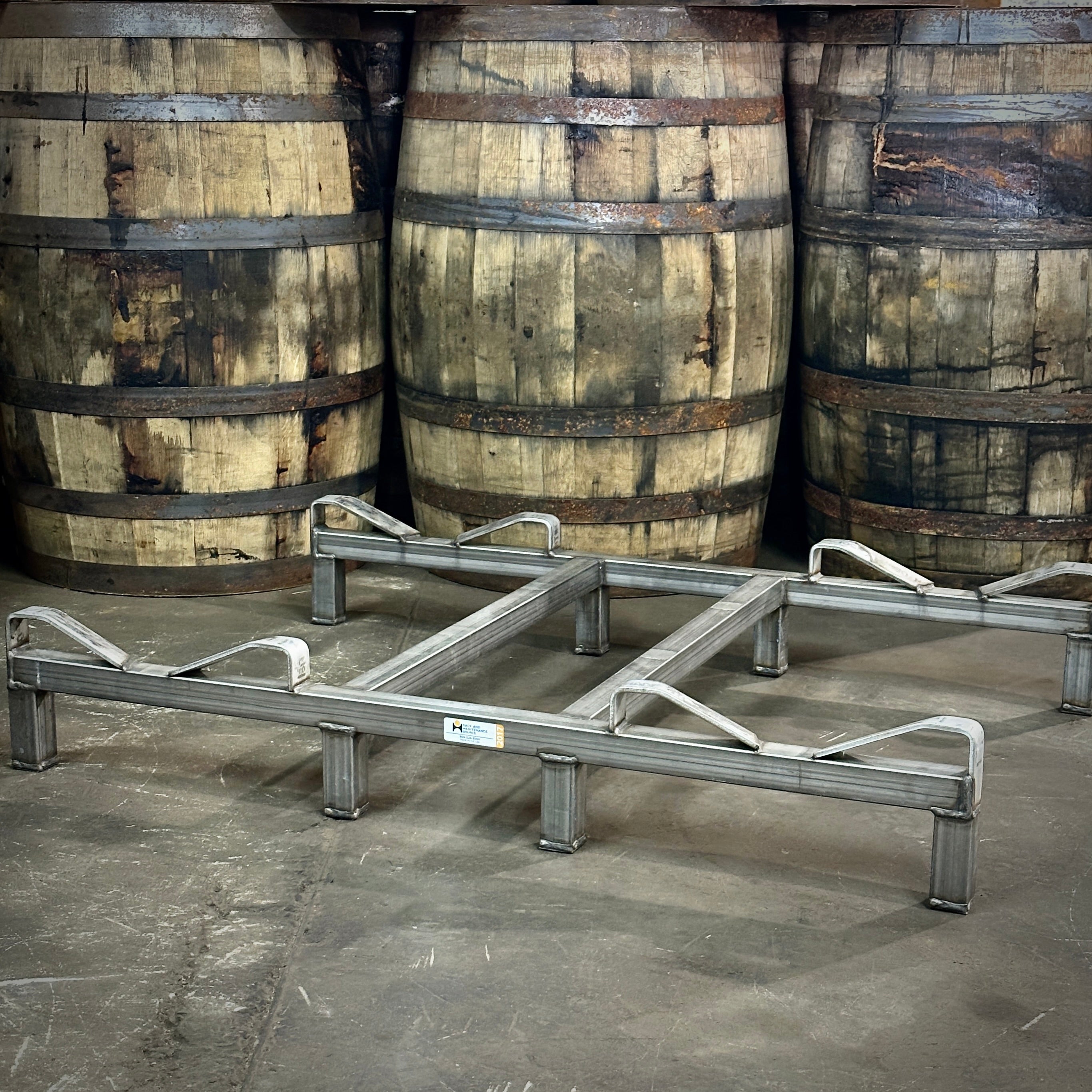 Metal pallets in front of wooden barrels on a concrete floor