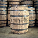Stack of wooden barrels with metal bands on a concrete floor