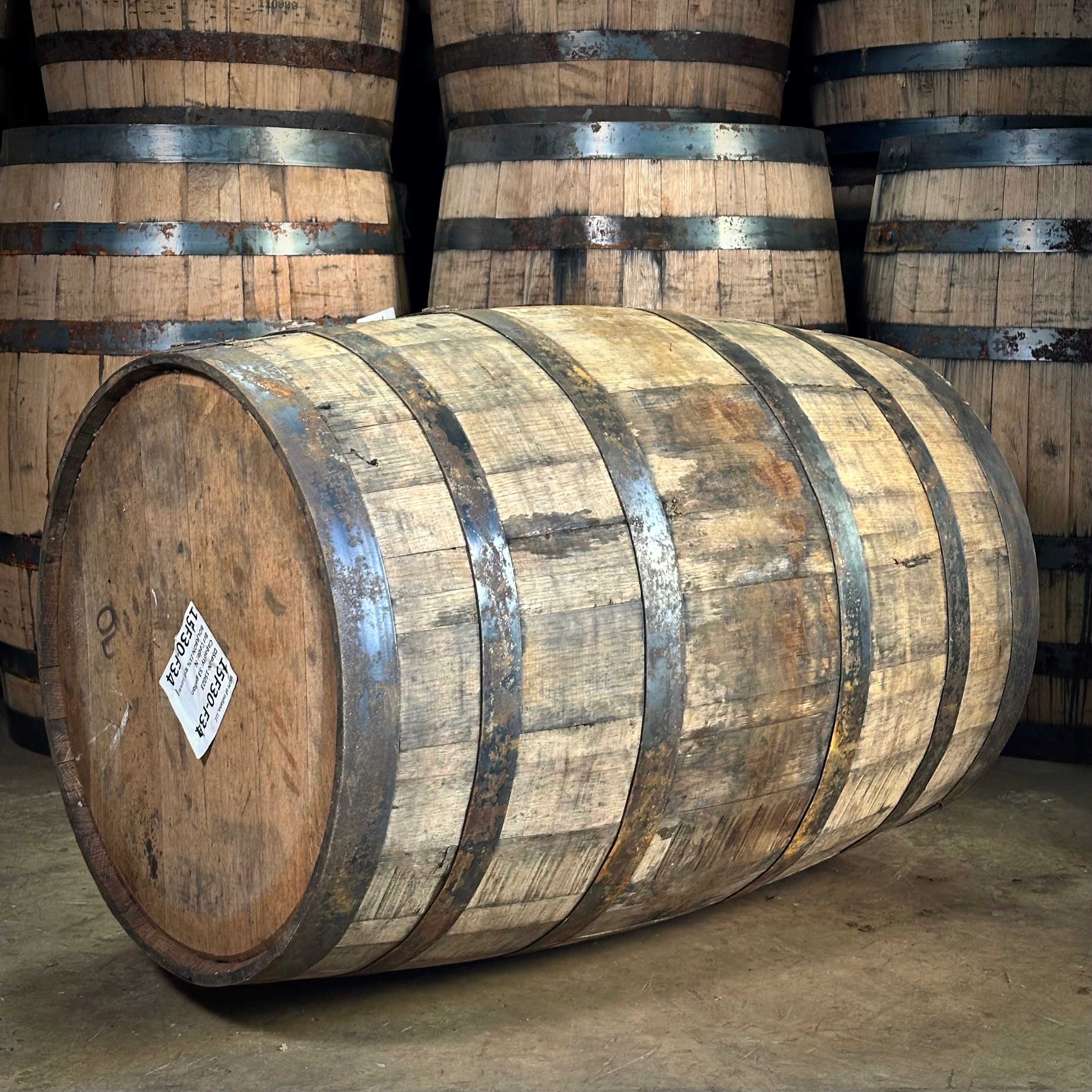 Wooden barrels with metal bands stacked in a warehouse setting