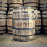 Stack of wooden barrels with metal bands on a concrete floor