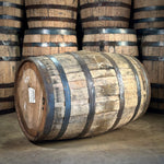 Wooden barrels with metal bands stacked in a warehouse setting