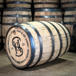 Wooden barrel with branding and text Salt Lake City Utah Sugar House Distillery stacked with other barrels in the background.