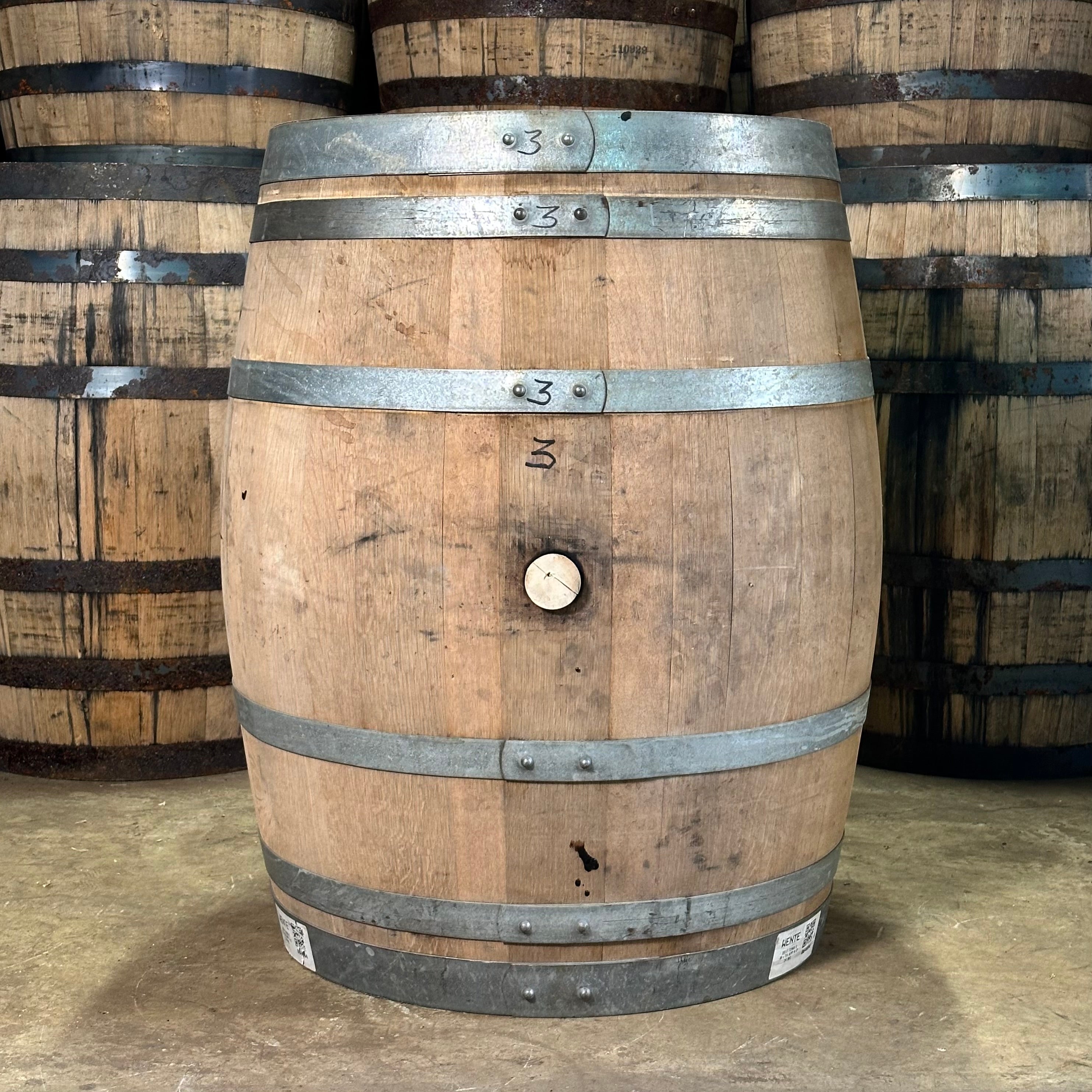 Wooden barrel with metal bands in a stack of similar barrels.